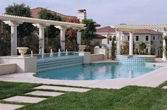 an outdoor swimming pool surrounded by white pillars