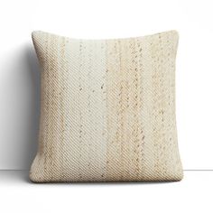 a white and beige pillow sitting on top of a wooden floor next to a wall