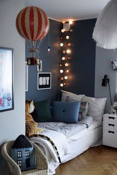 a bedroom decorated in blue and white with hot air balloons above the bed, lights on the wall