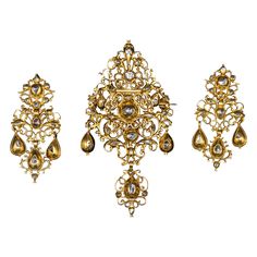 Museum-quality antique late 17th/early 18th century diamond and yellow gold Baroque "sequilé” earrings and pendant/brooch demi-parure, Portuguese, with hallmarks from the period and in the original case. This Georgian sequilé jewel from the first half of the 1700s features intricate filigree, pierced, and die-pressed gold work. It is closed-back set throughout with table-cut and rose-cut diamonds, notable for their almost crude simplicity. The pieces are richly adorned with chiseled and scallope 22k Gold Victorian Ceremonial Jewelry, Baroque Yellow Gold Ceremonial Jewelry, Ornate Baroque Jewelry With Rose Cut Diamonds, Antique Pendant Yellow Gold Earrings, Antique Yellow Gold Pendant Earrings, Baroque Rose Cut Diamond Jewelry For Wedding, Ornate Baroque Yellow Gold Jewelry, Ornate Ceremonial Jewelry With Rose Cut Diamonds, Ornate Jewelry With Rose Cut Diamonds For Ceremonial Use