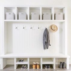 a white bench with shoes and hats on it next to a coat rack filled with bins