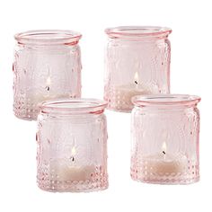 four pink glass jars with candles in them