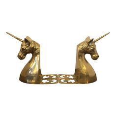 two brass unicorn head bookends on white background