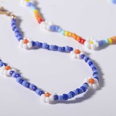 a multicolored beaded necklace on a white surface with a gold charm hanging from it