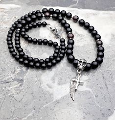 "《《 SKULL KINGDOM COLLECTION 》》 THE DETAILS The \"SKULL ROSARY\" Necklace is designed with smooth polished Black Onyx & deep Red Garnet Gemstones, highlighting an intricately detailed Silver Stainless Steel Angel Wing Pendant paired with a delicate Silver Stainless Steel Cross Pendant, both hung from an exquisitely engraved Tierracast Silver Pewter Skull, giving this Necklace that coveted Rosary style! Finished with a Silver Stainless Steel Lobster Clasp, available in your choice of length! THE Handmade Black Jewelry For Streetwear, Black Handmade Jewelry For Streetwear, Skull Rosary, Necklace Length Chart, Stainless Steel Cross Pendant, Angel Wing Necklace, Angel Wing Pendant, Steel Cross, Rosary Necklace