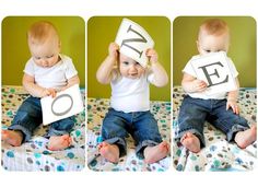 a baby sitting on top of a bed holding up signs