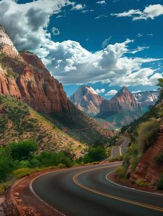 the road is winding through the mountains with clouds in the sky