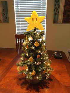 a small christmas tree with yellow decorations on it's top and lights around the base