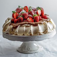 a cake with frosting and strawberries on top is sitting on a white platter