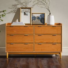 a wooden dresser sitting on top of a hard wood floor next to a potted plant