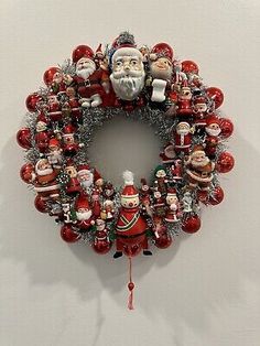 a christmas wreath hanging on the wall with santa claus and other ornaments attached to it