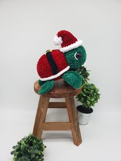 a stuffed turtle wearing a santa hat on top of a wooden stool