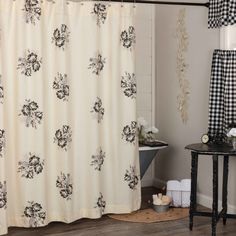 a black and white shower curtain with flowers on it in a bathroom next to a stool