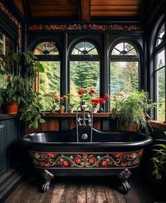 an old fashioned bathtub with flowers in the window sill and potted plants