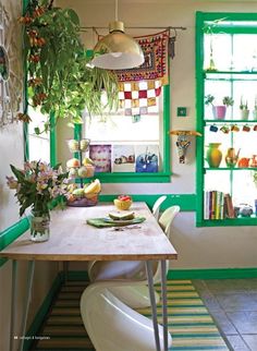 a dining room with green windows and plants on the table, along with other decorations