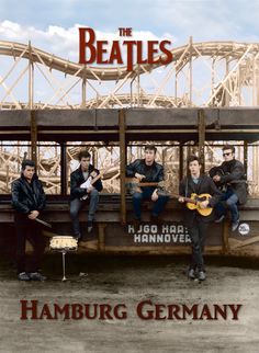 the beatles sitting on top of a bench in front of a bridge and holding a sign