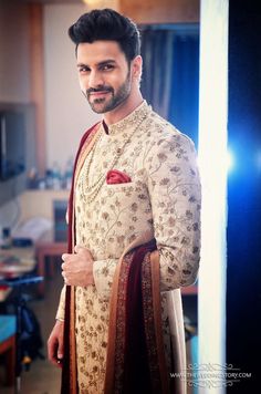 the man is wearing a white and red outfit with gold details on his chest, standing in front of a mirror