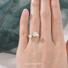 a woman's hand with a diamond ring on top of her finger and the other hand holding an engagement ring