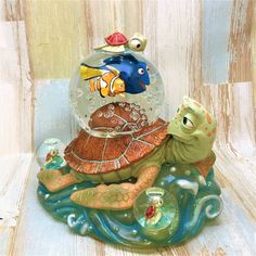 a glass figurine sitting on top of a turtle with a fish in it's shell