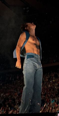 a man standing on top of a stage with his shirt off and hands in the air