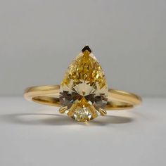 a fancy yellow diamond ring sitting on top of a table