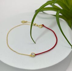 Discover timeless elegance with our exquisite Bezel Set Certified Moissanite Red Cord & Chain Bracelet, designed to grace your wrist with a touch of opulent glamour. Crafted in luxurious 14K Yellow Gold Plated Sterling Silver, this bracelet seamlessly blends classic sophistication with contemporary charm. Adorned with a dazzling Certified Moissanite gemstone, and expertly bezel-set to ensure maximum brilliance and durability, this bracelet is a true testament to refined luxury. The fiery radiance of the Moissanite stone captures attention from every angle, making it an ideal statement piece for any occasion. Embracing versatility, the adjustable Red Cord & Chain design ensures a perfect fit for any wrist size, while maintaining comfort and style. The vibrant red cord adds a pop of color, c Red Diamond Bracelet Gift, Red Diamond Jubilee Bracelet Gift, Love Bracelet, Gifts For My Wife, Cord Bracelet, Chain Design, Minimalist Bracelet, Cord Bracelets, Love Bracelets