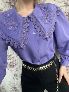 A vintage purple blouse, beautifully adorned with intricate embroidery, capturing the essence of 1970s fashion. This shirt is distinguished by its puritan collar, adding an elegant and modest touch. The rich purple fabric serves as a vibrant backdrop for the detailed embroidery, creating a striking contrast. Its design combines retro charm with sophistication, making it a unique and eye-catching garment. - Good vintage condition (small fabric wrinkle on the back, see photo) - TAG SIZE: No inform Spring Purple Collared Blouse, Spring Purple Blouse With Collar, Purple Blouse With Ruffled Collar, Elegant Embroidered Blouse With Peter Pan Collar, Elegant Collared Purple Top, Elegant Purple Collared Top, Elegant Lavender Blouse For Party, Elegant Lavender Party Blouse, Classic Collared Purple Blouse