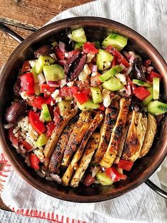 a bowl filled with chicken, cucumber and tomato salad on top of a wooden table