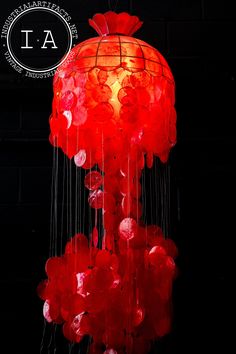 a red lamp hanging from the ceiling in front of a brick wall