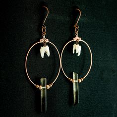 These smoky quartz crystal earrings are an elegant choice in real animal bone taxidermy jewelry. Each antiqued copper hoop has a real stone crystal surrounded by delicate metal beads that hang beneath a genuine raccoon tooth. These medium weight earrings make a bold statement while staying muted and classy. A wonderful gift for that someone who loves a little oddity. -Smoky quartz crystal points -Real taxidermy raccoon teeth -Dainty metal beads -Antiqued copper hoop charm -Lever back earring clo Oddity Jewelry, Bone Taxidermy, Raccoon Teeth, Animal Bone Jewelry, Oddities Jewelry, Tooth Earrings, Taxidermy Jewelry, Architectural Jewelry, Goth Earrings