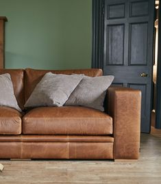 a brown leather couch sitting on top of a hard wood floor