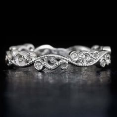 a white gold wedding band with diamonds on the sides and an intricate design in the middle