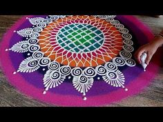 someone is drawing on the ground with colored chalks and glue to make an intricate design