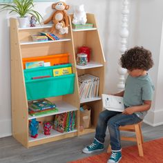 a young boy sitting on a chair reading a book in front of a bookshelf