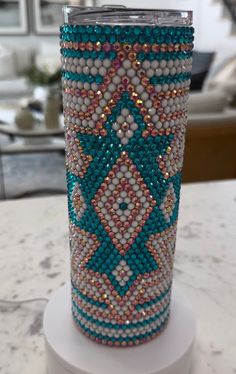 a glass with some beads on it sitting on a white stand in front of a table