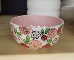 a bowl with flowers painted on it sitting on a table next to plates and bowls