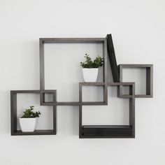 three square shelves with plants in them against a white wall