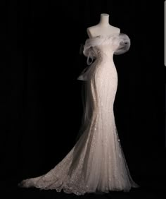 the back of a wedding dress on display in front of a black background with white fabric