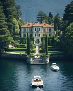 two boats are in the water near a large house with trees and bushes around it