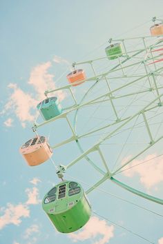 the ferris wheel is green and has four seats for people to ride on it's sides