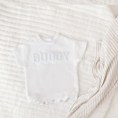 "Celebrate your sweetie with this piece featuring a white embroidered lettered text on a white colored romper. This sweet piece is the perfect romper for baby. The design is made on a 100% cotton fabric, light sweatshirt material. It is cozy soft and perfect for staying cuddly. This romper is oversized in style in a baby sweatshirt bubble romper design. Select the words you would like in the \"personalization\" section. Your word of choice must be under 7 in order to fit across the chest. Please note: the letters themselves are pre-embroidered and are transferred to the product using heat :) This product is handprinted using nontoxic, water-based inks. Gentle cycle on cold inside out, lay flat to dry or gentle cycle for best results. Do not iron over design. Product will come packaged with Casual Personalized White Onesie, Casual White Personalized Onesie, White Short Sleeve Cotton Bodysuit, Cotton Baptism Onesie With Short Sleeves, White Short Sleeve Onesie For Baptism, White Cotton Crew Neck Onesie, White Short Sleeve Bodysuit With Letter Print, White Cotton Onesie With Name Print, White Letter-printed Short Sleeve Bodysuit