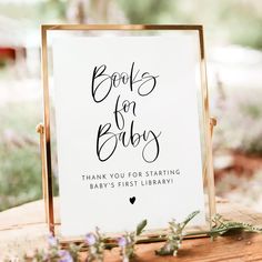 a sign that says books for babys on top of a wooden table with flowers