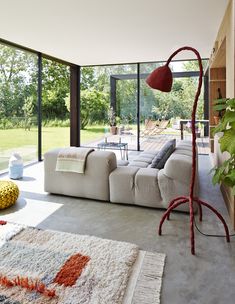 a living room filled with furniture next to a large glass window covered in lots of windows