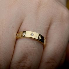 a close up of a person's hand wearing a ring with stars on it