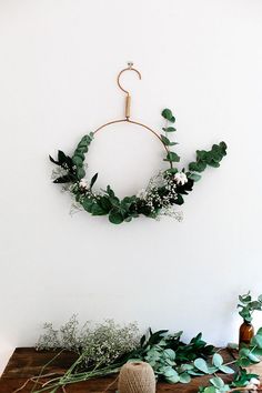 a wooden table topped with greenery and a wreath hanging on the wall above it