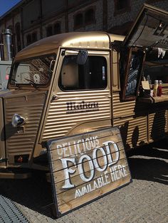 an old food truck is parked in front of a building with its door open and there is a sign that says, get out of the food available here