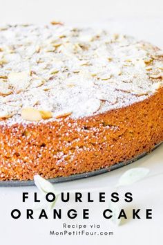 an orange cake with powdered sugar and almonds on top, sitting on a white plate