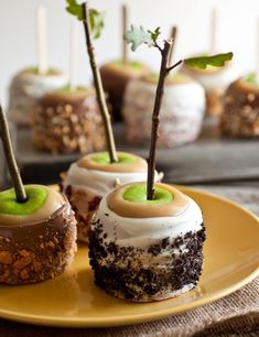 four desserts on a yellow plate with green apples in the middle and small trees sticking out of them