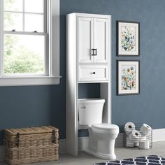 a white toilet sitting next to a tall cabinet in a blue room with pictures on the wall