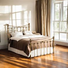 a bed sitting on top of a wooden floor next to a window